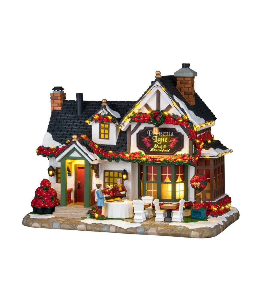 Lemax Poinsettia Lane Bed & Breakfast 65525: casa vacanze illuminata con stelle di Natale e tavolo all'aperto